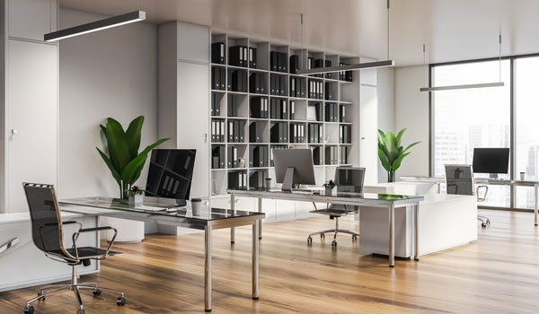Open office plan with floor-to-ceiling shelving and white and gray furniture.
